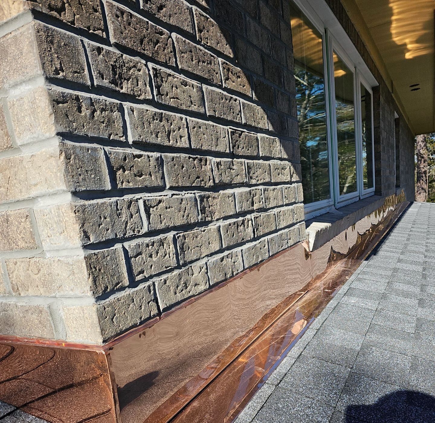 Long copper flashing detail along a brick wall