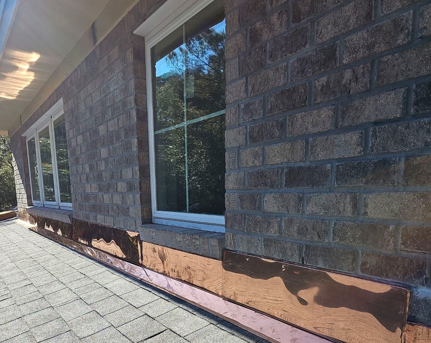 New copper flashing installed along a brick wall